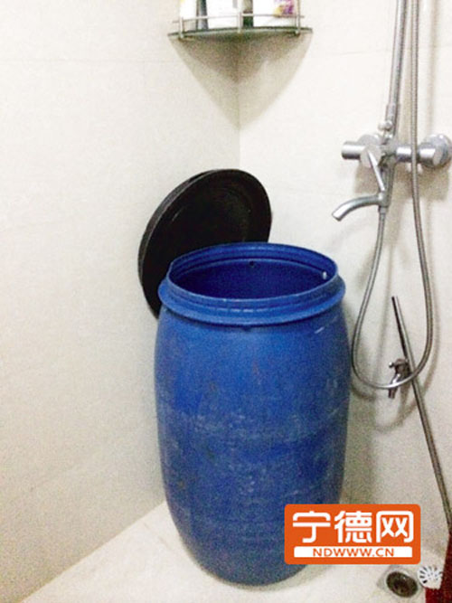 业主余先生家的卫生间摆放着一个超大的塑料桶用来接水。