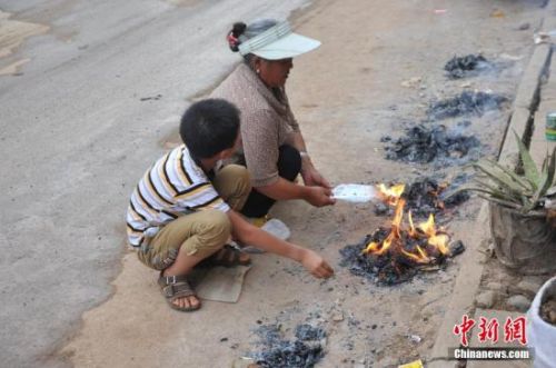 8月8日,云南鲁甸县民众在公路边烧纸钱祭奠在地震中逝去的亲人。张浪 摄