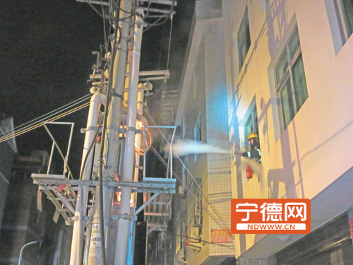 救援人员站在居民楼灭火。