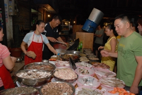 入夜，大排档和烧烤摊纷纷现身街头，食材摆满长桌供食客选择，烤架和炒锅旁不断有浓烟升起