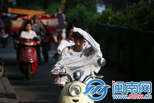 昨天紫外线强，一位穿防晒衣的市民用手遮太阳