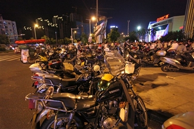 晚上，先锋广场外的机动车道上违章停靠了许多电动车和摩托车。