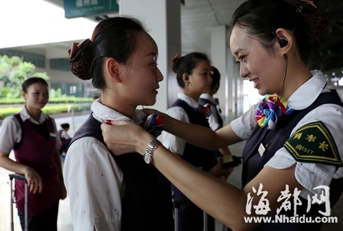 列车长张文静给班组乘务员整理着装