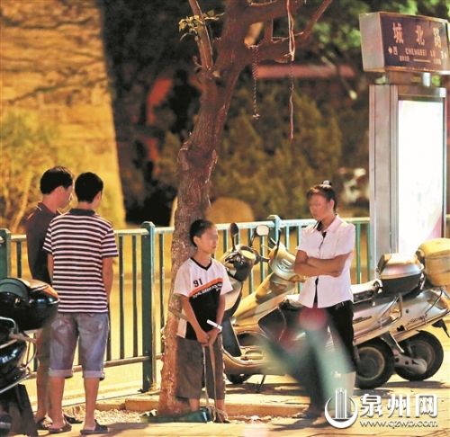 孩子被绑在树上，一旁站着他母亲。