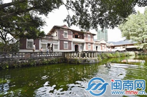 红砖古厝结构对称，楼前有一湾水池，两侧各植一棵大榕树