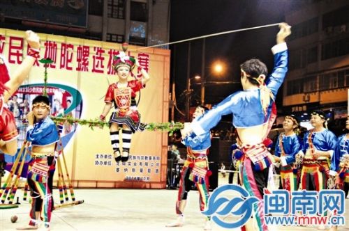 陀螺表演者稳稳地将陀螺抛进姑娘的帽子里