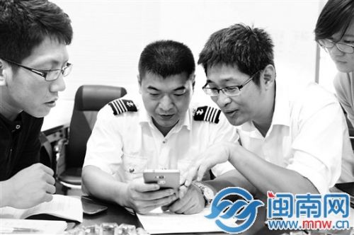 “海峡号”船长（中）向海都记者展示照片