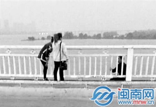 妻子（黄衣）到现场劝解，男子仍在桥护栏外