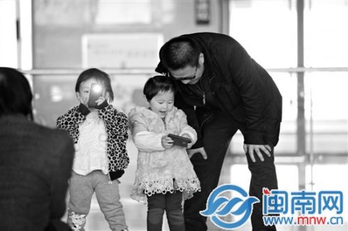 元旦增开多趟动车，市民轻松出行，图为漳州动车站两个父亲陪小孩玩手机