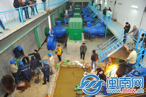 水厂车间内一片繁忙，工人正在抓紧更换设施