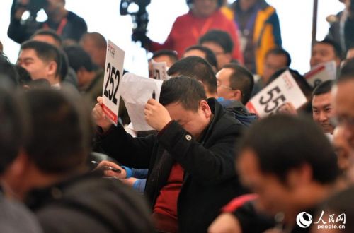 拍得首辆车的252号买主用卡牌挡住了媒体记者的镜头。