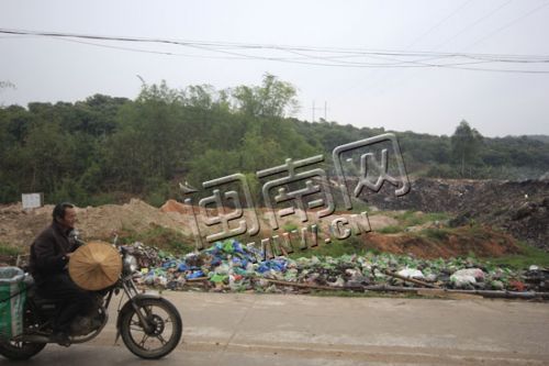 后方的垃圾场浓烟已消,但路边又出现一个新的垃圾堆