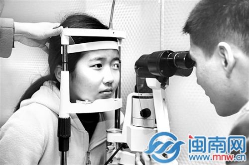医生对被测者（左）的眼睛进行检测