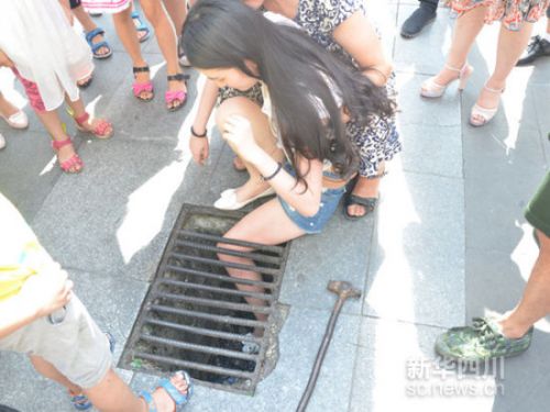 女孩走路玩手机太专注 腿卡进下水道