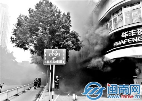 起火店面冒出的滚滚浓烟，弥漫到路面上