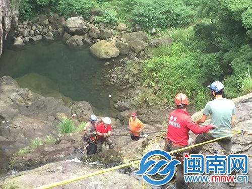 悬崖上方有救援者在拉绳，下方还有救援者在保护驴友