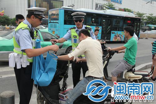 民警拆下电动车上的遮阳伞，并对骑车者批评教育