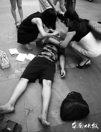 两名女子正在对倒地男子进行救助
