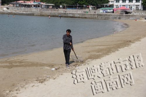 一位清洁工正在清理残余垃圾，石湖湾沙滩已干净许多