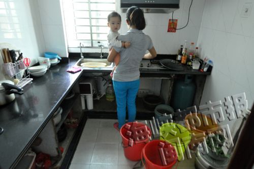 一女住戶家中廚房，擺滿水桶