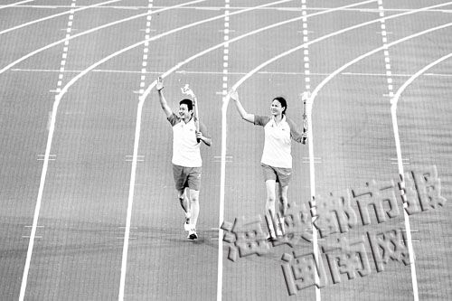 第一棒火炬手陈忠和与侯玉珠跑进了体育场