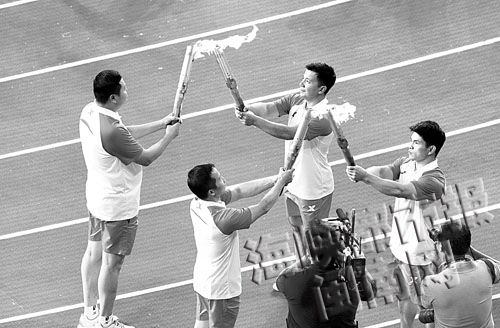 第二棒的石智勇和吉新鹏，向第三棒的张湘祥和林清峰传递火炬