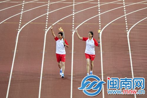 第一棒火炬手陈忠和与侯玉珠跑进了体育场
