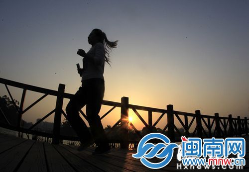 夕阳下，市民沿着西湖栈道慢跑