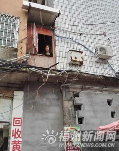 一楼主通道被封，张先生的妹妹从二楼探出头来与记者交流。