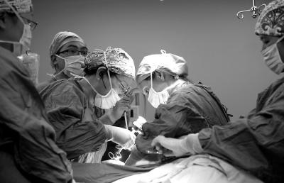 黄勉与两名外籍专家一起为患者做腹腔镜手术 医院供图