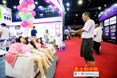 现场一名男士对着充气娃娃拍照