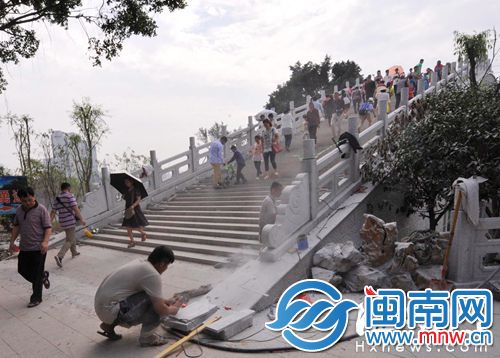 桥上游人如织，工人在一旁施工