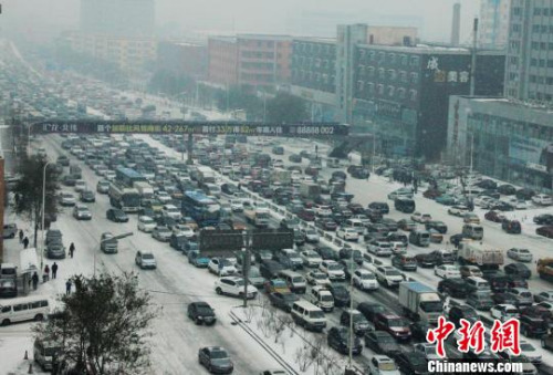 降雪后市区主干道内缓慢的车流。　王栋梁　摄