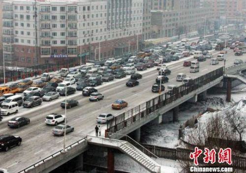 9日凌晨起，位于中国境内纬度最高的省会城市&mdash;&mdash;哈尔滨市迎来今年冬天的首场降雪。图为降雪后市区主干道内缓慢的车流。　王栋梁　摄