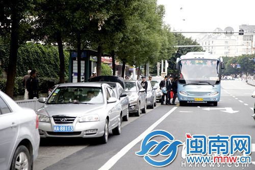 洪山桥小区公交站前的路面，被一排违停小车所占，公交车无法进站