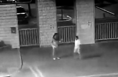 监控视频中，毕国昌拿着相机请路人帮忙拍照。