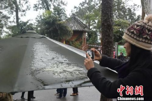 一名摄影爱好者爬上高处拍摄遮阳伞上的积雪。