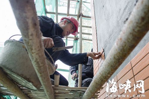 工人正给落架的教学楼贴瓷砖
