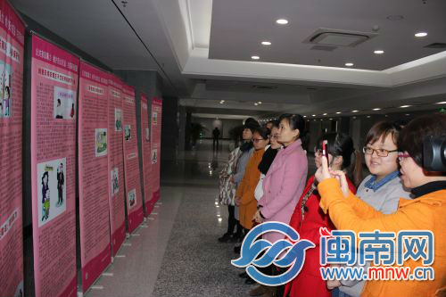 图为妇女群众观看反家庭暴力法宣传展板