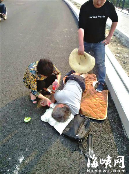 好心人让老人躺在垫子上，林芳帮老人湿润嘴唇，小柯帮忙扇风（网友供图）
