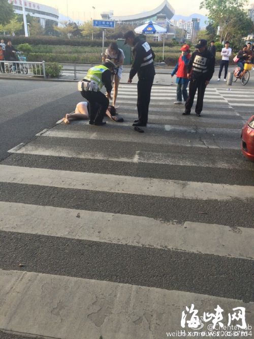 二环五四路口，两女闯红灯过街，其中一人被撞倒地，交警和协警拦住过往车辆，防止她被碾（网友供图）