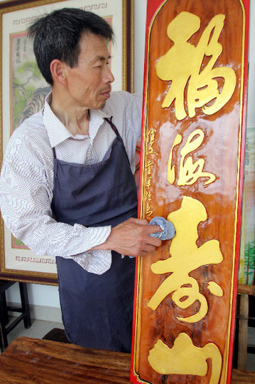 4月23日，陈绍椿在工作室擦拭作品&ldquo;福海寿山&rdquo;木雕刻漆匾