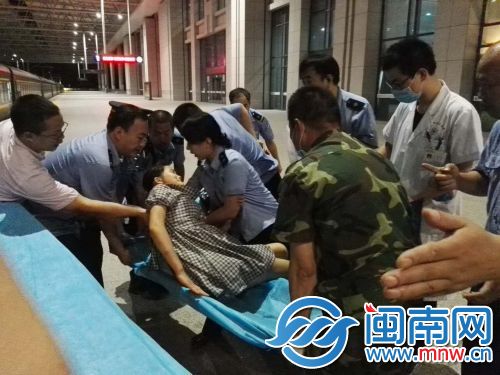 孕妇在车站工作人员和医务人员的帮助下躺上急救担架