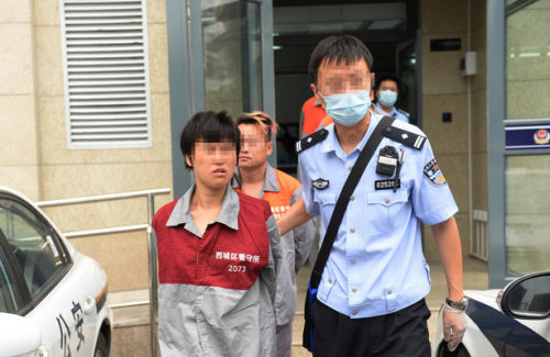 2016年7月12日,中国北京,7月8日凌晨5时许,在西城区什刹海南官房胡同内,30岁的流浪女曹某和一名男子因琐事发生争吵,后持铁链抽打对方,导致男子经抢救无效死亡。因认为石景山是座山,便于躲藏,曾有过持刀伤人前科的曹某开始骑车向西逃跑,当她发现自己误判后,又骑着车折返回西城。图为民警将曹某带离执法办案中心,送往看守所。