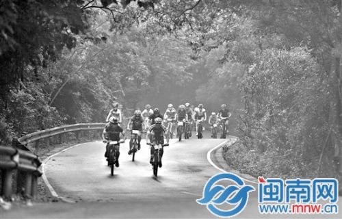 比赛选手冒雨骑行在蜿蜒的山道上