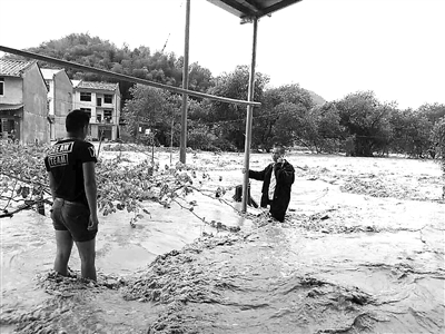 民警涉险穿越滚滚洪流，为了防止被洪水冲走民警抓住路边的铁柱子