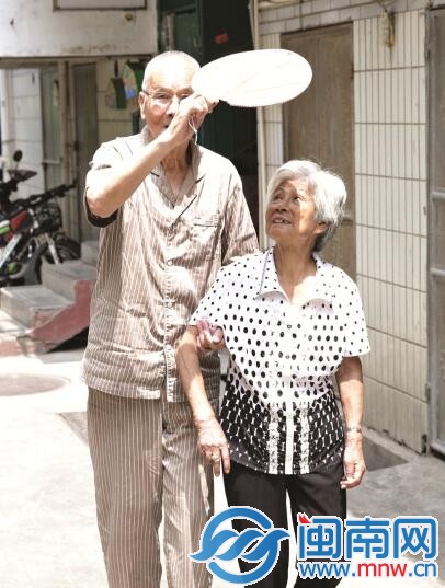 大热天出门，阿伯会用扇子帮老伴挡阳光