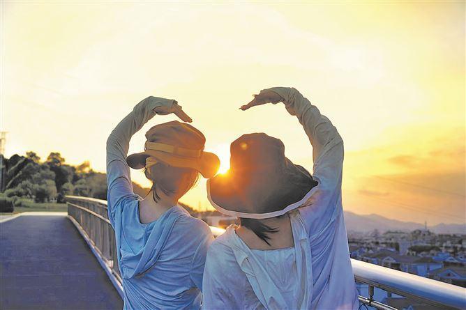 小姐妹“比心”，跟夕阳合影。（厦门日报拍客 何燕欣 摄）