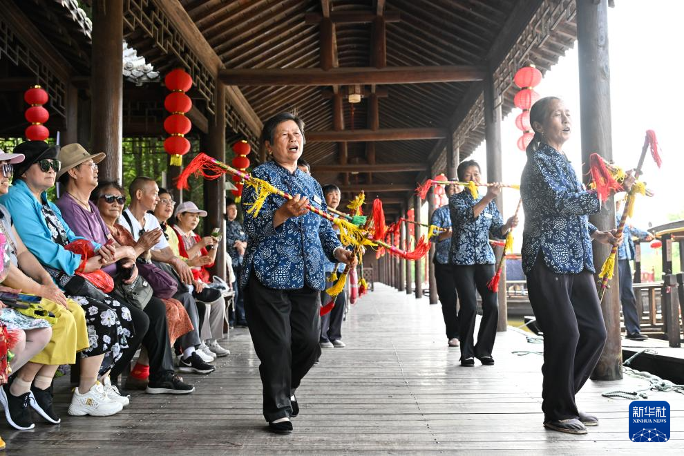 6月4日，在泰州市姜堰区溱湖国家湿地公园，船娘给游客表演非遗滚莲湘。新华社记者 季春鹏 摄