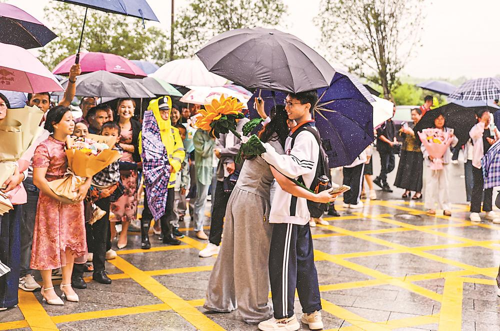 9日,三明市建宁县第一中学考点,考生走出考场和冒雨前来的家长深情相拥,合影留念。通讯员 陈震 记者 庄紫怡 摄